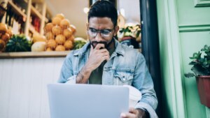 Small business owner reviewing a suspicious invoice email on his laptop, a common sign of email impersonation scams